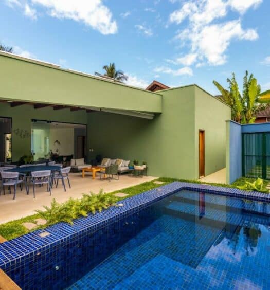 Área de lazer da Casa Patropi na Praia de Guaecá durante o dia com piscina a frente do lado direito da imagem e do lado esquerdo a propriedade. Representa airbnb na praia de Guaecá.