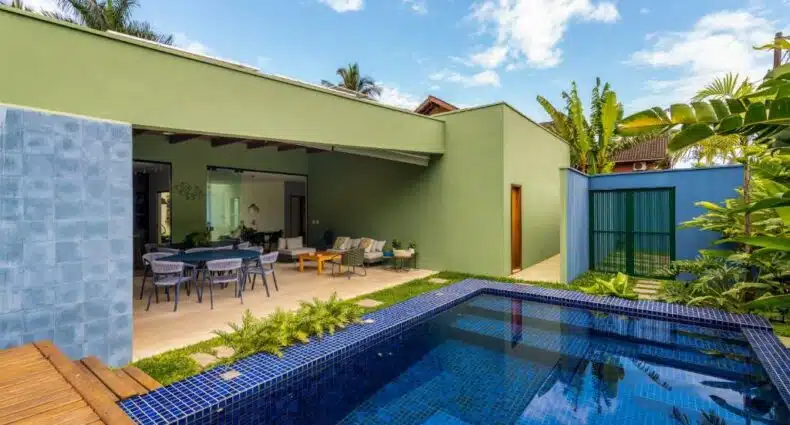 Área de lazer da Casa Patropi na Praia de Guaecá durante o dia com piscina a frente do lado direito da imagem e do lado esquerdo a propriedade. Representa airbnb na praia de Guaecá.
