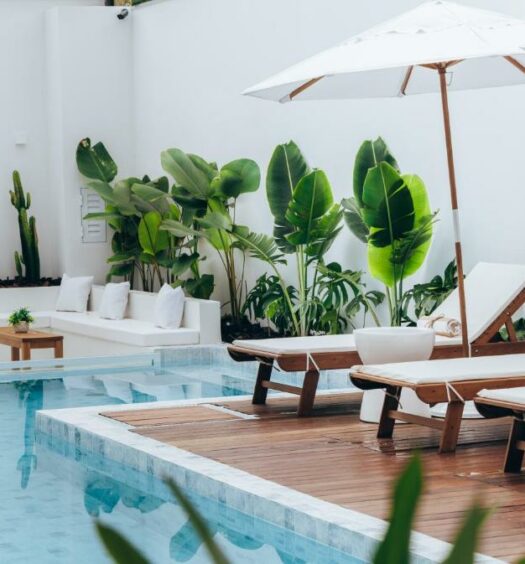 Área da piscina do Olisa Hotel Boutique durante o dia com piscina do lado esquerdo da imagem e do lado direito cadeiras na borda da piscina. Representa airbnb em São Sebastião.