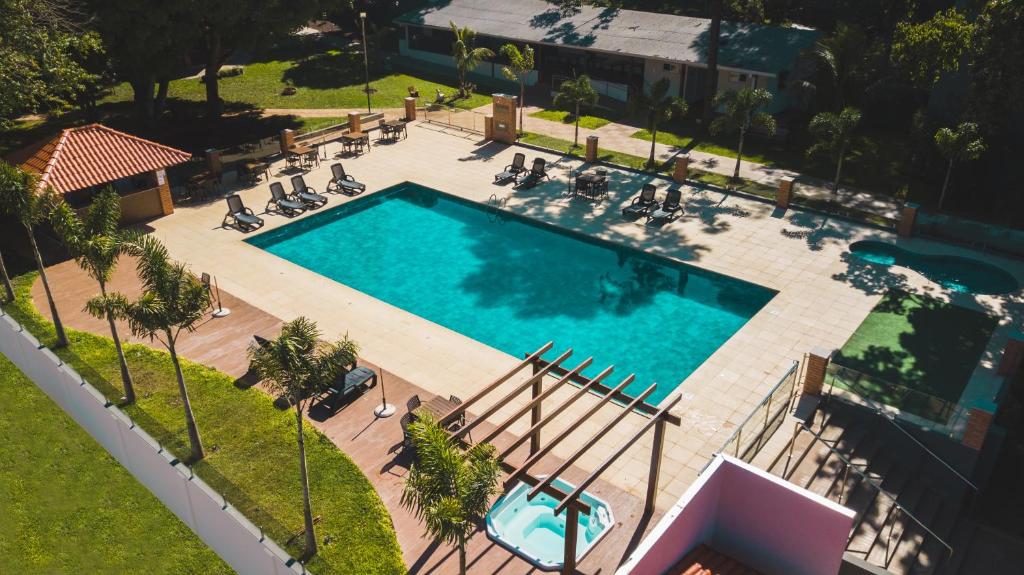 Parte do Cataratas Park Hotel com uma piscina retangular ao ar livre e algumas espreguiçadeiras em volta. O lugar tem gramado em volta, quiosque, árvores e uma banheira. Imagem ilustrando post Hotéis em Foz do Iguaçu.