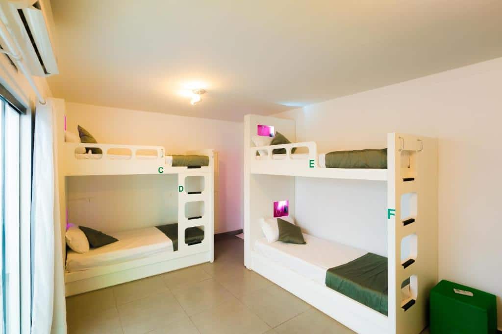 Foto do quarto do Concept Design Hostel & Suítes, ilustrando o post sobre Onde ficar em Foz do Iguaçu. Mostra duas beliches, uma encostada na parede à direita e outra na parede central. Na esquerda há uma janela.