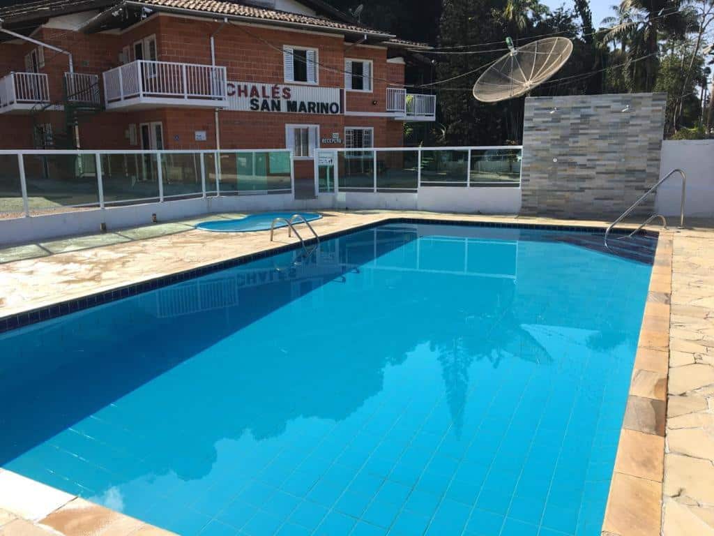 Área externa do Cond Apartamentos Chalés San Marino. Uma piscina de adulto, no fundo uma piscina infantil.