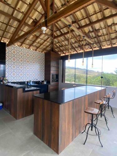 Cozinha da Casa vista da serra com uma banqueta do lado direito com três cadeiras e a trás da banqueta a cozinha.