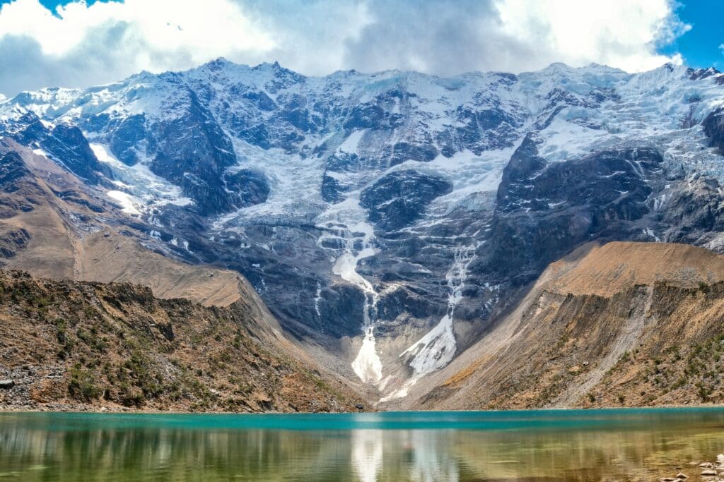 lago de água congelado das montanhas de Humantay, no Peru. Ao fundo é possível ver a cordilheira dos andes peruanos com suas montanhas congeladas, descendo gelo até o lago.