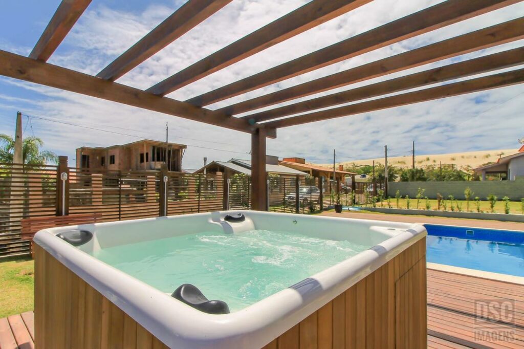 Hidro nas Dunas Studios. Uma cobertura com ripas de madeira fica logo acima, e ao fundo está a piscina e o jardim.