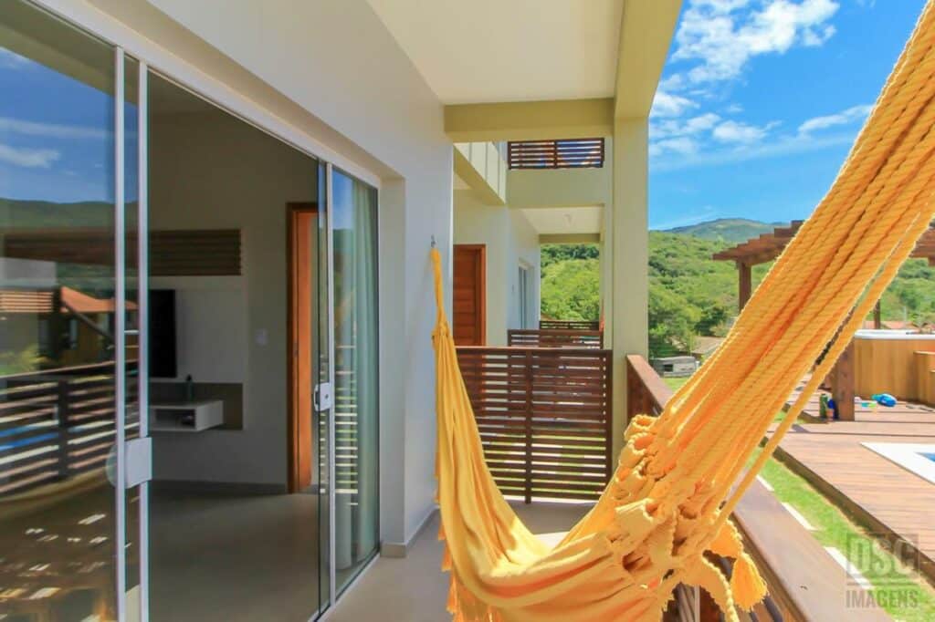 Sacada das Dunas Studios com rede. Na lateral esquerda fica a porta de vidro com entrada para a sala, e ao lado direito há vista para a piscina.