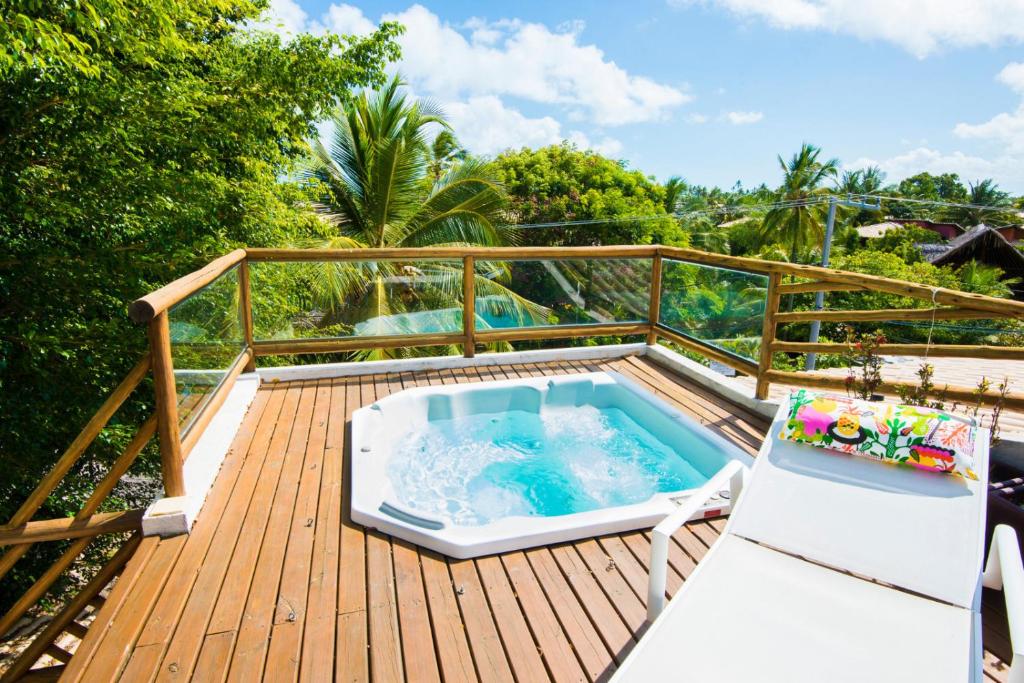 Terraço com piso de madeira, hidromassagem e espreguiçadeira no Duplex com hidromassagem - Praia do Forte. A vista é par várias árvores praianas.