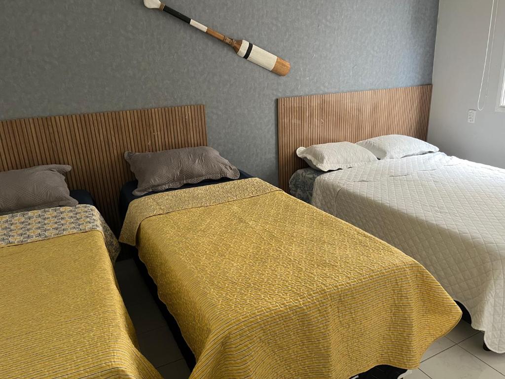 Foto de um quarto no Guarujá Flat com duas camas de solteiro e uma de casal, uma ao lado da outra. 
