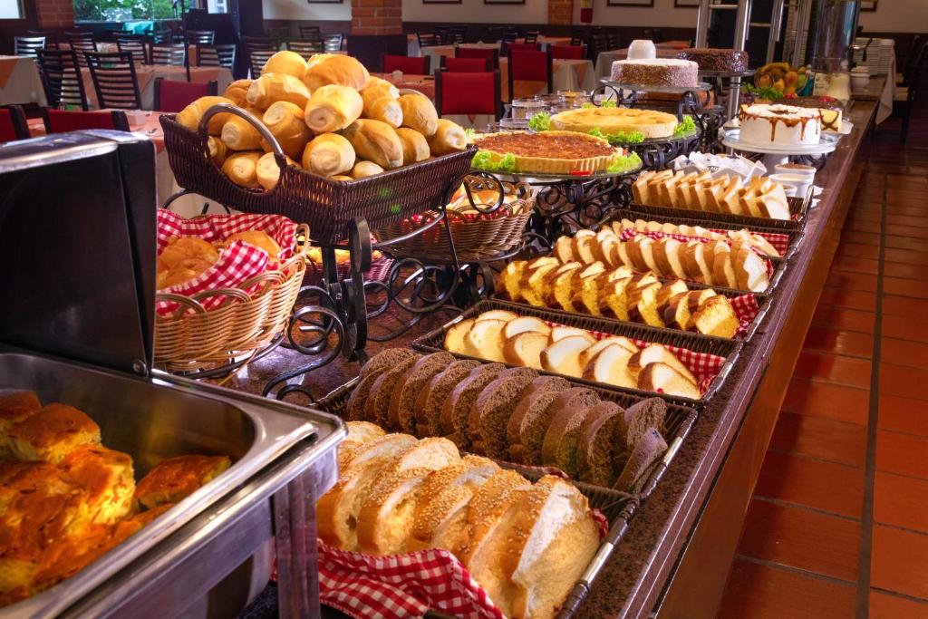 Foto do Hotel Colonial Iguaçu, mostrando uma bancada com vários alimentos com pães, bolos, tortas, doces, etc.