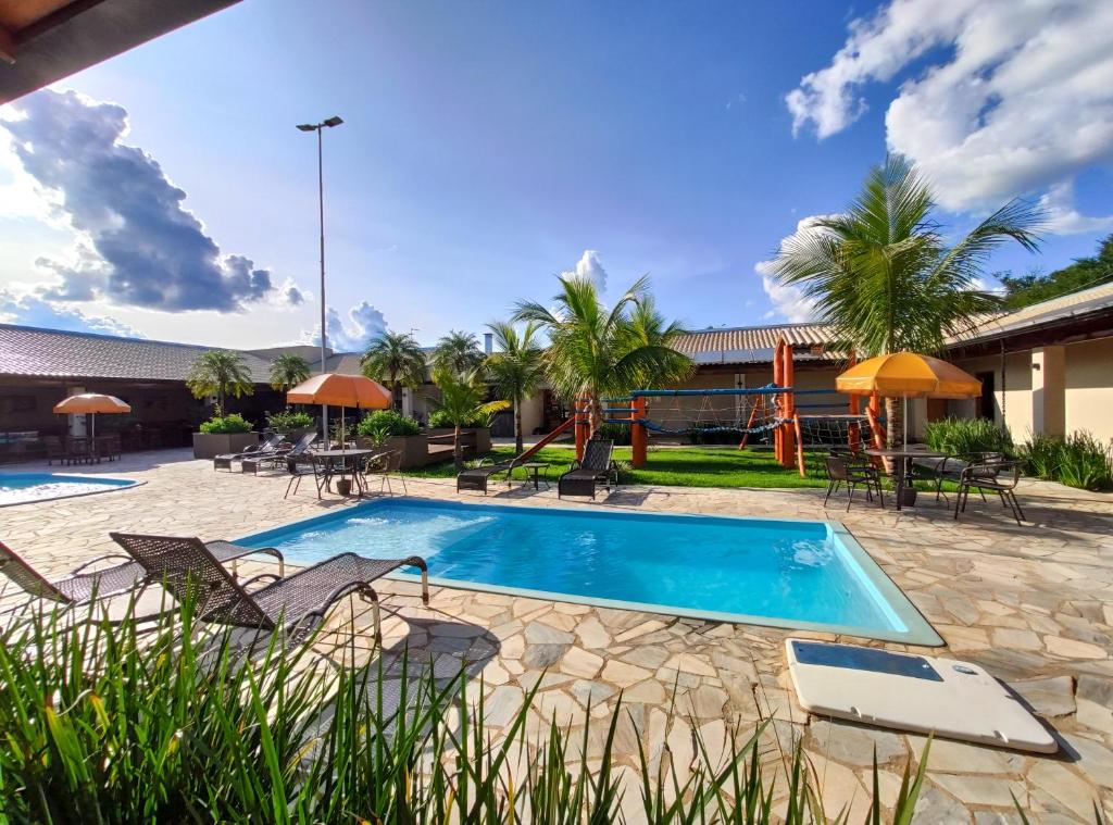Área verde com piscina no Hotel Pousada Parque das Águas, próximo da piscina há também um parquinho infantil e algumas palmeiras