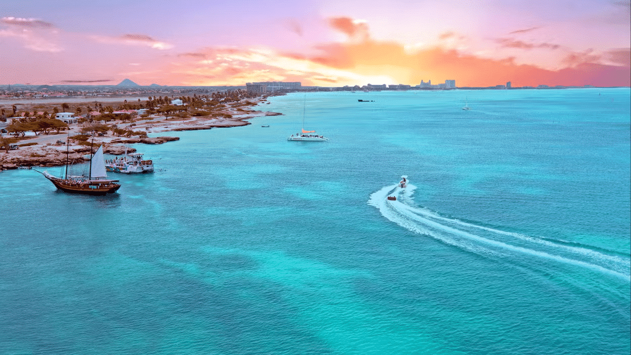 Imagem do mar de Aruba durante o dia com mar a frente e alguns barcos dentro do mar.