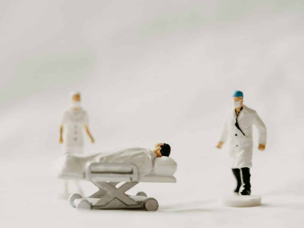 miniaturas de médicos atendendo pacientes em uma maca para ilustrar o post de o que é DMH