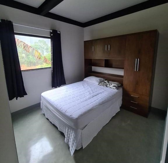 Quarto do Moderna do Prumirim. Uma cama de casal está no meio de um armário na parede. Ao lado há uma janela.