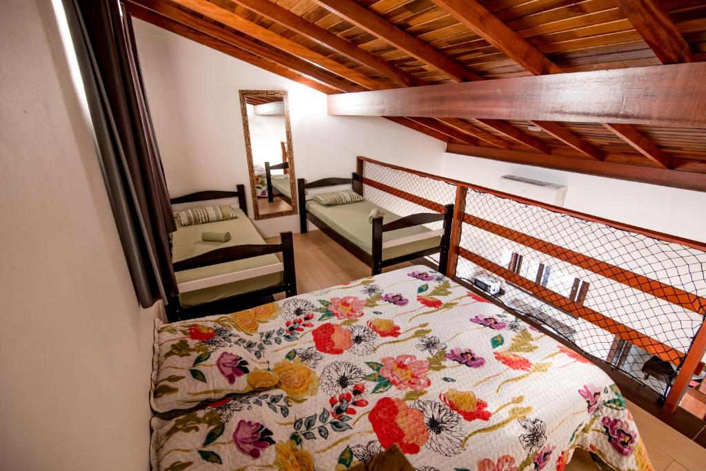 Camas no mezanino da Morada Canto Norte - Apartamentos Beira Mar, airbnb em Garopaba. Uma cama de casal fica no primeiro plano, e ao fundo há duas camas de solteiro com um espelho entre si.