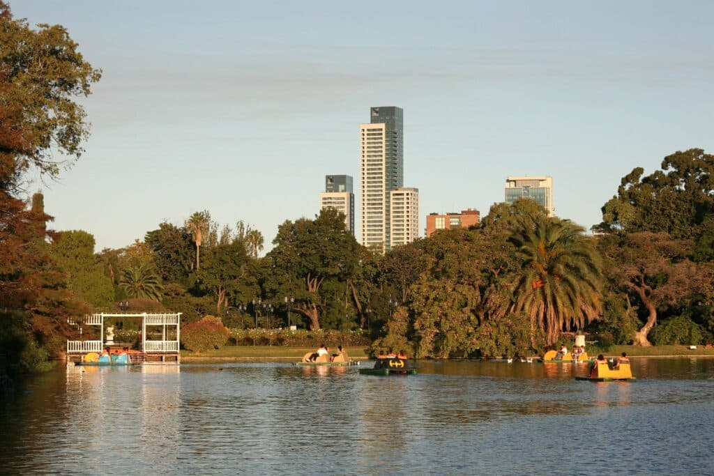 Lago do parque El Rosedal, no bairro Palermo. Algumas pessoas estão em pedalinhos, e ao fundo há árvores.
