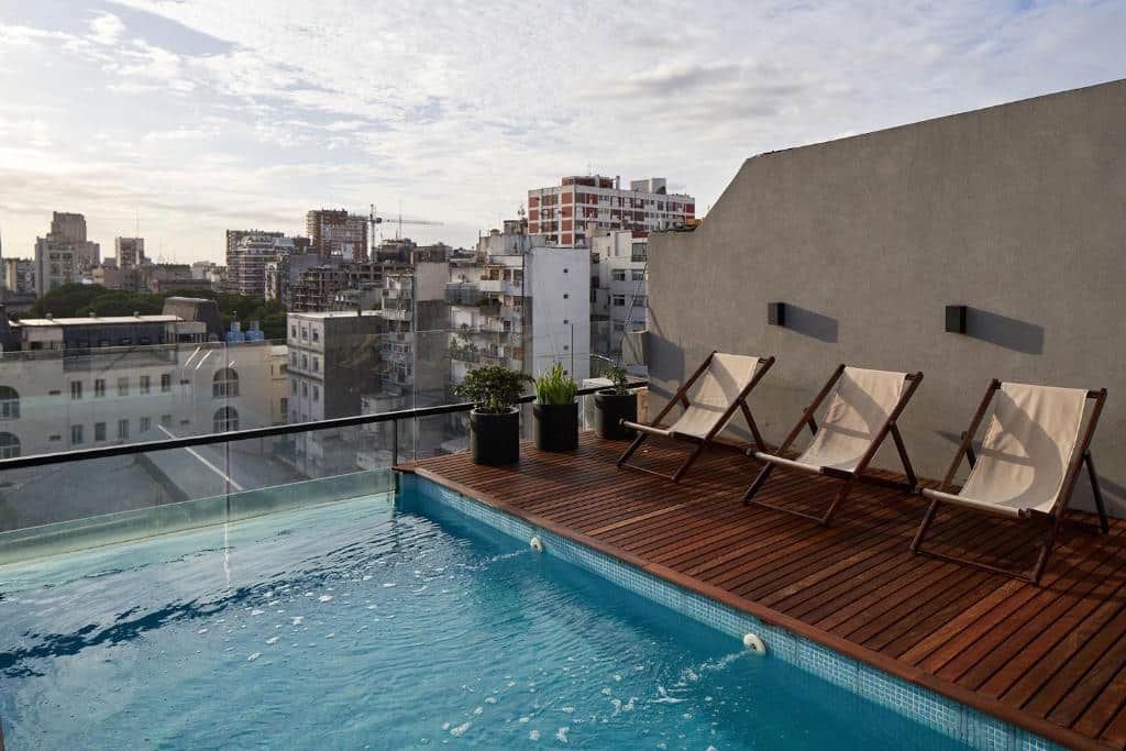 piscina retangular no terraço com espreguiçadeiras trançadas e vista da cidade no AQ Tailored Suites, um dos hotéis de luxo para família em Buenos Aires