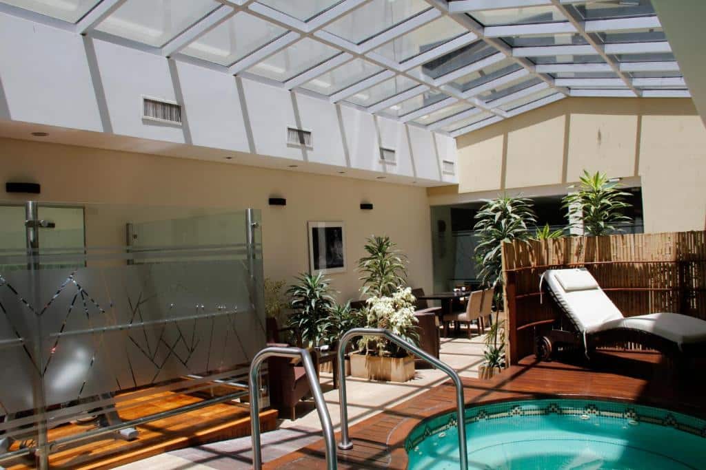 piscina coberta com teto de vidro, escadinha de segurança, espreguiçadeiras e ducha privativa no Blank Hotel Recoleta, um dos hotéis de luxo em Buenos Aires