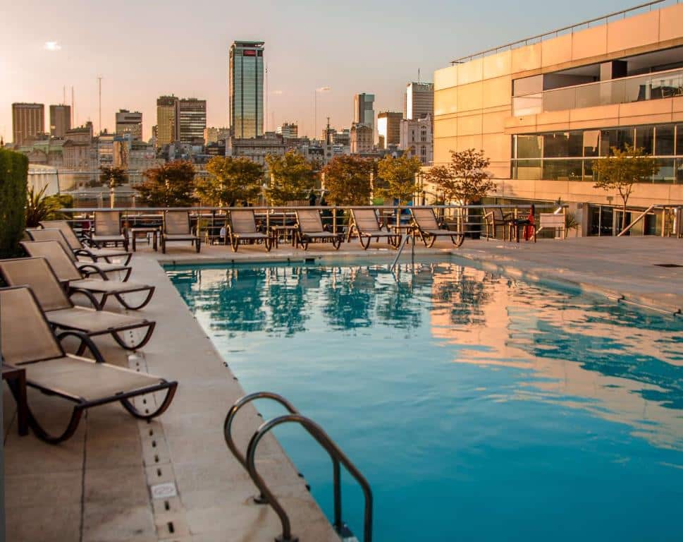 piscina retangular no terraço ao pôr do sol com vista para os prédios e espreguiçadeiras ao redor no Hilton Buenos Aires, um dos hotéis de luxo em Buenos Aires