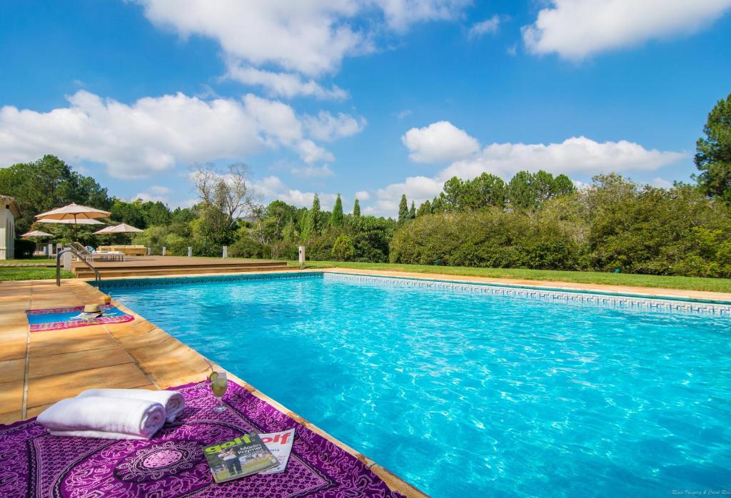 Imagem da piscina do Garden Hill Hotel e Golfe durante o dia com piscina com piscina do lado direito da imagem do lado esquerdo na borda algumas toalhas. Representa airbnb em São João del Rei.