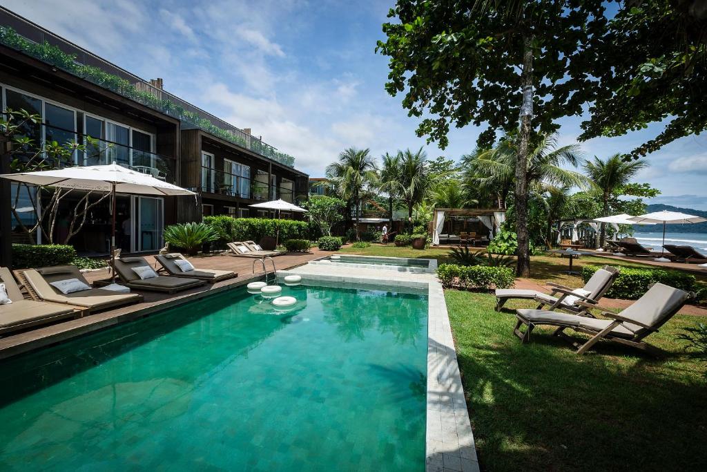 Piscina ao ar livre do Hotel Spa Nau Royal com piscina do lado esquerdo da imagem e em cada lado da cama cadeiras.