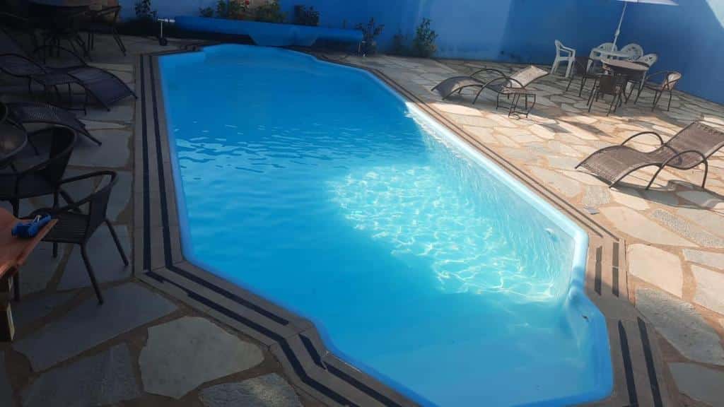 Área externa da Pousada Estrela Guia. No meio uma piscina, de cada lado cadeiras de tomar sol.