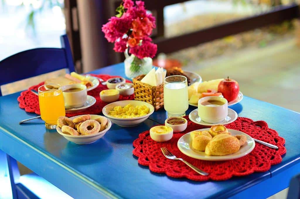 Uma mesa posta para duas pessoas com uma grande variedade de café da manhã da Pousada Rancho do Ralf.