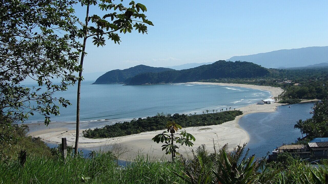 Vista da Praia Barra do Una, onde as ondas calmas desembocam na areia. Uma faixa de vegetação separa o rio do mar. - Foto: Jurema Oliveira via Wikimedia Commons