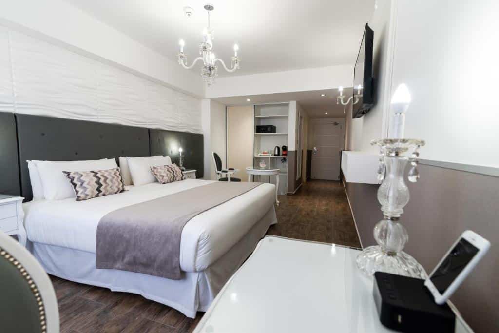Quarto amplo do Ker San Telmo Hotel com cama de casal, tv em frente e escrivaninha, do lado há uma mesa com cadeiras e estante com comodidades para fazer chá, para representar hotéis perto da Casa Rosada em Buenos Aires.