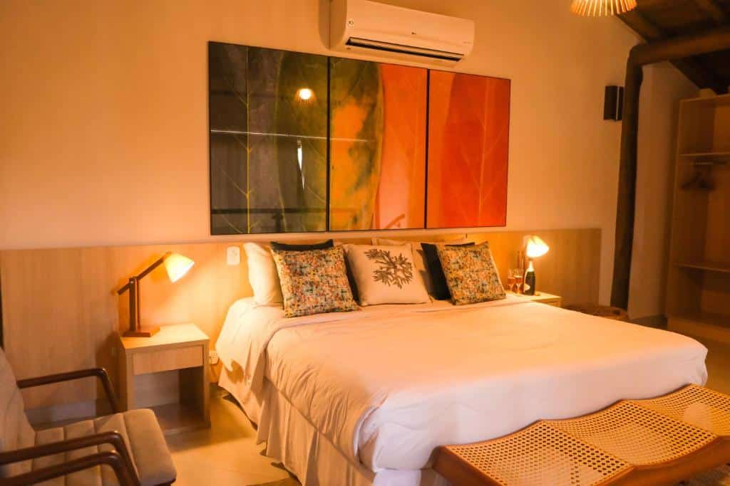 Quarto do Abricó Beach Hotel com cama de casal no centro da imagem com uma cômoda em cada lado da cama com luminária do lado esquerdo da cama uma poltrona. Representa hotéis em São Sebastião.