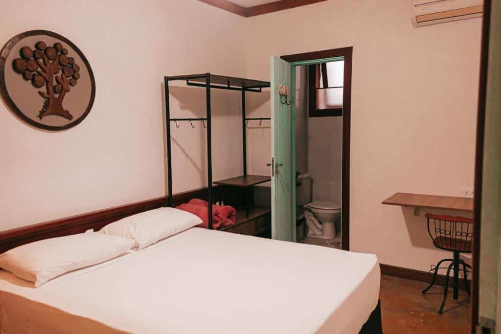 Quarto do Atlantic Hospedagem com cama de casal do lado esquerdo da imagem, do lado esquerdo da cama uma estante. Representa hotéis em São Sebastião.