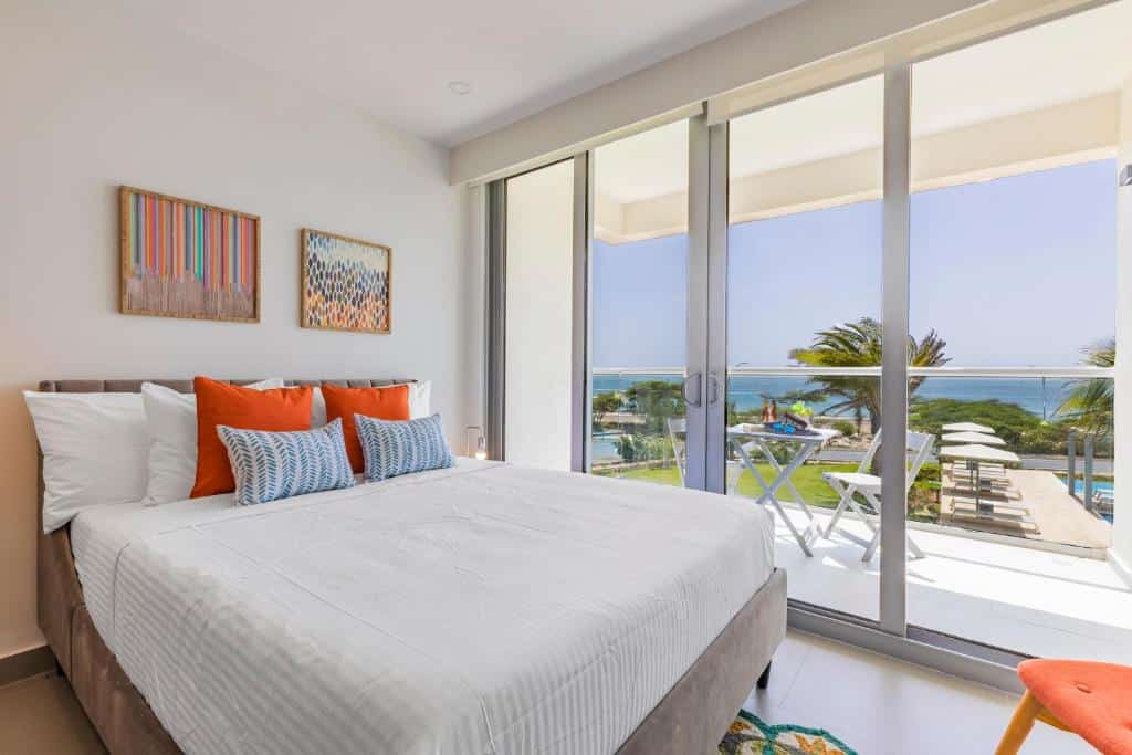 Quarto do Azure Beach Residences com cama de casal do lado esquerdo da imagem do lado esquerdo da cama um porta de vidro que dá acesso a varanda.  Representa Aruba.