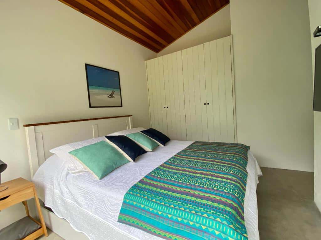 Quarto da Casa Amendoeiras – spa aquecido e wifi com cama de casal do lado esquerdo da imagem com uma cômoda do lado esquerdo da cama. Representa airbnb na praia de Guaecá.