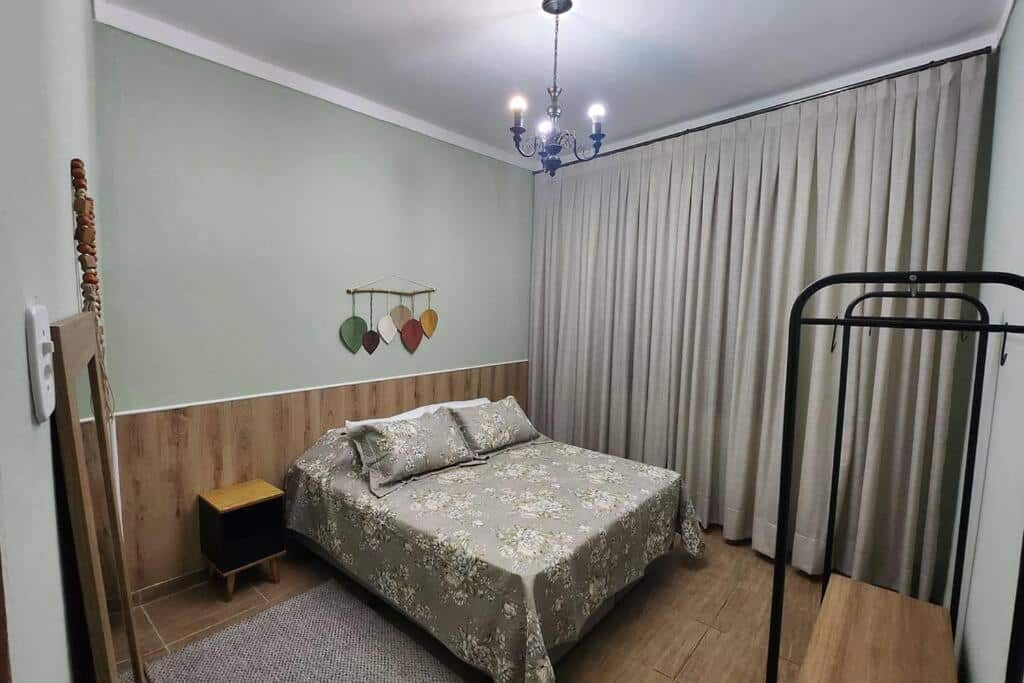 Quarto da Casa dos Sinos com cama de casal do lado esquerdo da imagem uma cômoda do lado direito da cama. Representa airbnb em São João del Rei.
