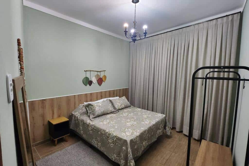 Quarto da Casa dos Sinos com cama de casal do lado esquerdo da imagem uma cômoda do lado direito da cama. Representa airbnb em São João del Rei.
