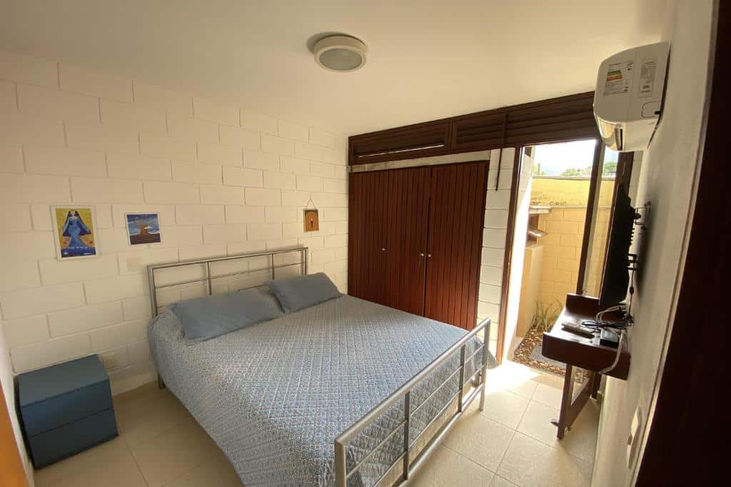 Quarto da Casa Espetacular com Jacuzzi Churrasqueira e WIFI com cama de casal do lado esquerdo da imagem no centro do quarto e em frente a cama uma cômoda com TV na parede. Representa airbnb na praia de Guaecá.