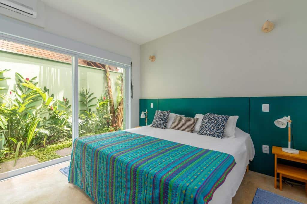 Quarto da Casa Patropi na Praia de Guaecá com cama de casal no centro do ambiente com uma cômoda em cada lado da cama com luminária. Representa airbnb na praia de Guaecá.