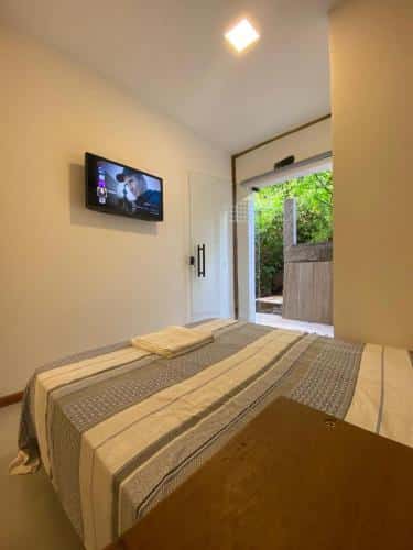 Quarto do Estúdio Vista Mar com cama de casal do lado direito da imagem e em frente a cama na parede na uma TV presa.