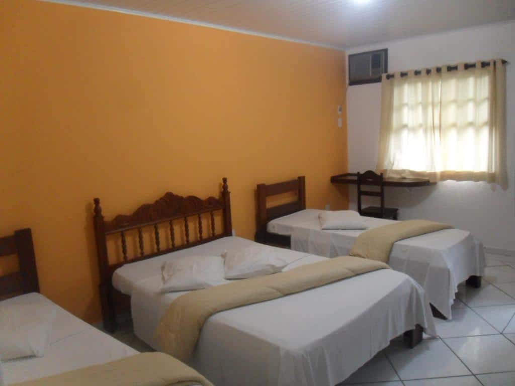 Quarto familiar do Hotel Roma com cama cama de solteiro do lado esquerdo da imagem, do lado esquerdo da cama de solteiro uma cama de casal e do lado da cama de casal outra cama de solteiro.