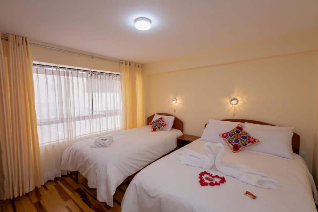 quarto do Hawka Inka Hostal - Cusco com duas camas, uma de casal e outra de solteiro, dispostas lado a lado.