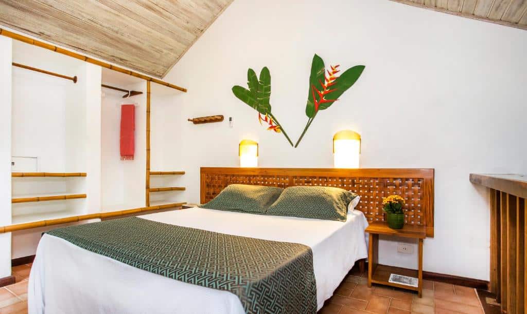 Quarto do Hotel Aldeia de Sahy com cama de casal no centro do ambiente e em cada lado da cama uma cômoda em cada lado da cama. Representa airbnb em São Sebastião.