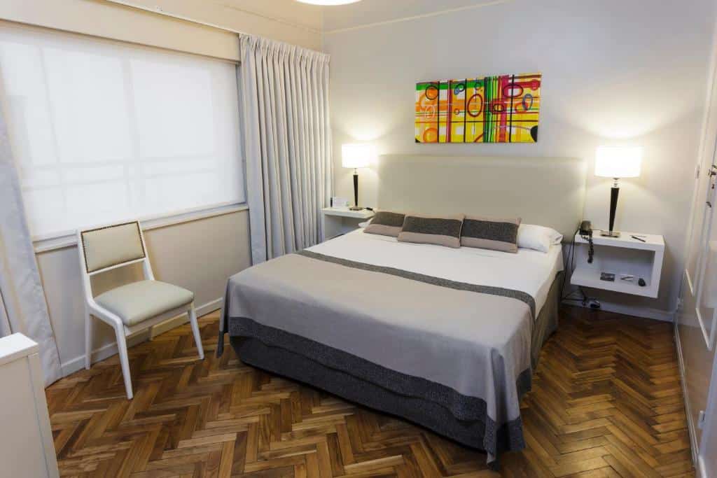 Quarto do Hotel Facon Grande com uma cama de casal, janela ampla, mesinhas de cabeceira e uma cadeira