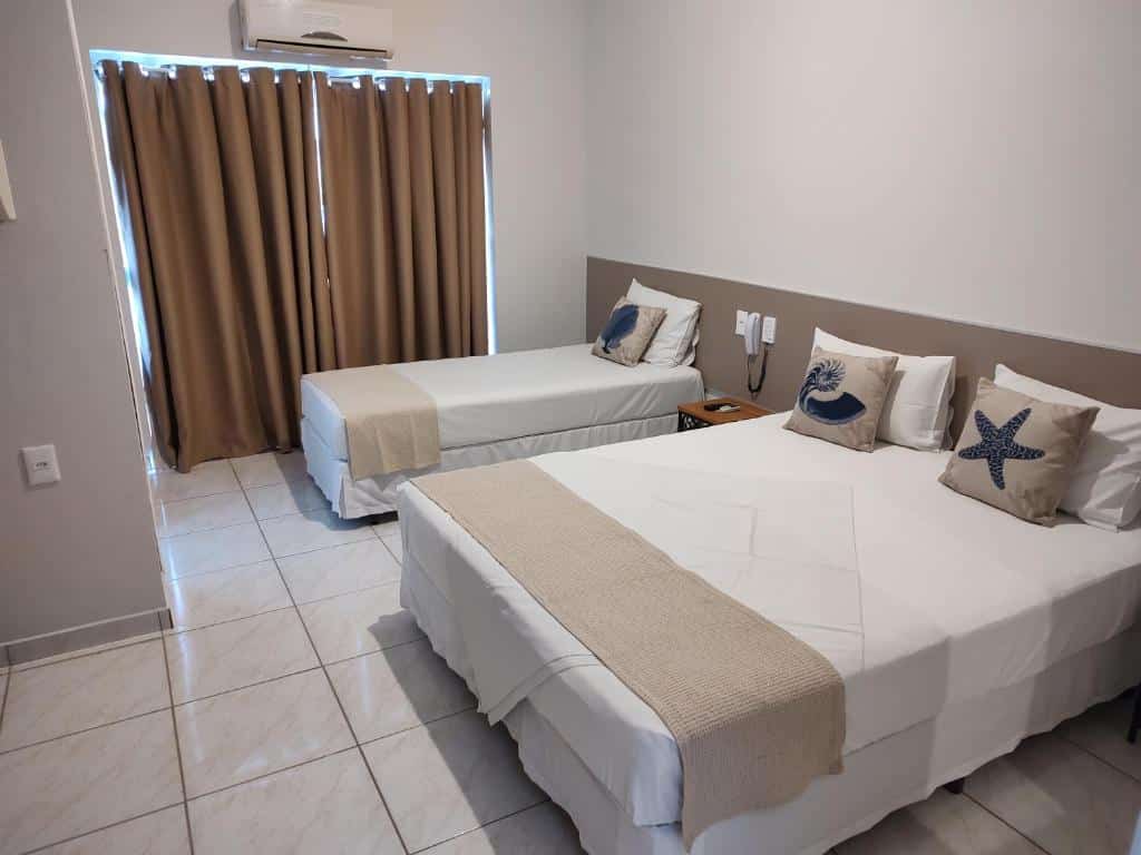 Quarto do Hotel Guarda Mor com cama de casal do lado direito da imagem e do lado direito da cama uma cômoda e depois uma cama de solteiro. Representa hotéis em São Sebastião.