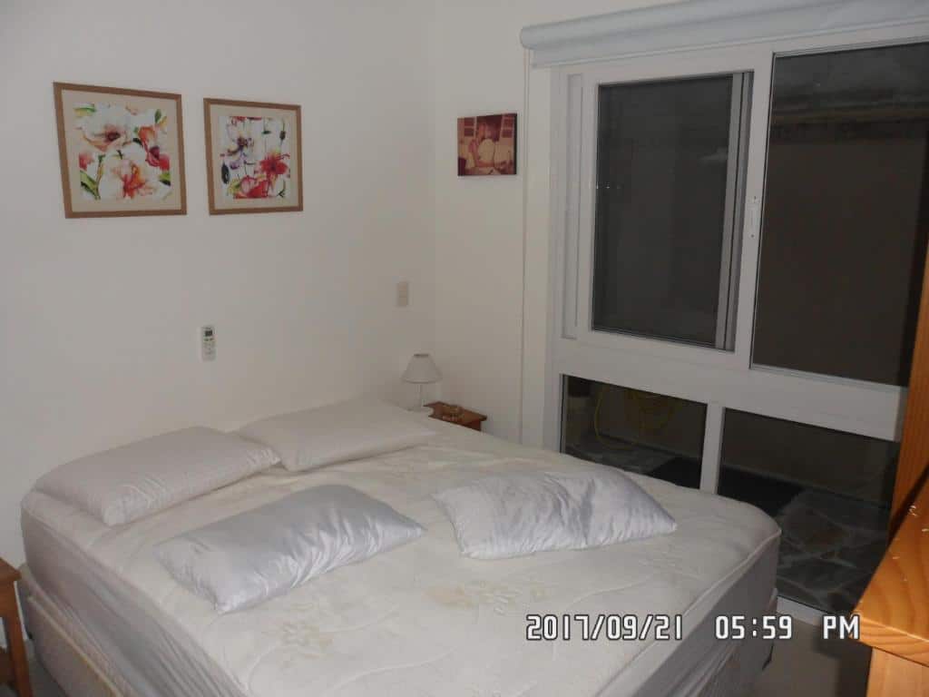 Quarto do Linda Casa em Juquehy com cama de casal do lado esquerdo da imagem e do lado esquerdo da cama uma cômoda com luminária. Representa airbnb na praia do Engenho.