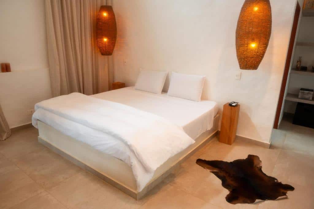 Quarto do Nai com cama de casal no centro do quarto com duas luminárias presas no teto. Representa airbnb em São Sebastião.
