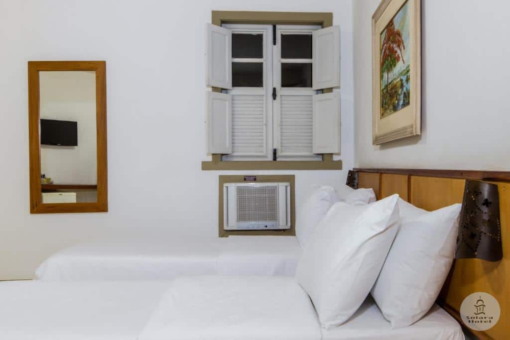 Quarto do Solara Hotel com cama de solteiro do lado direito da imagem a frente  e do lado direito da cama outra cama de solteiro. Representa airbnb em São João del Rei.