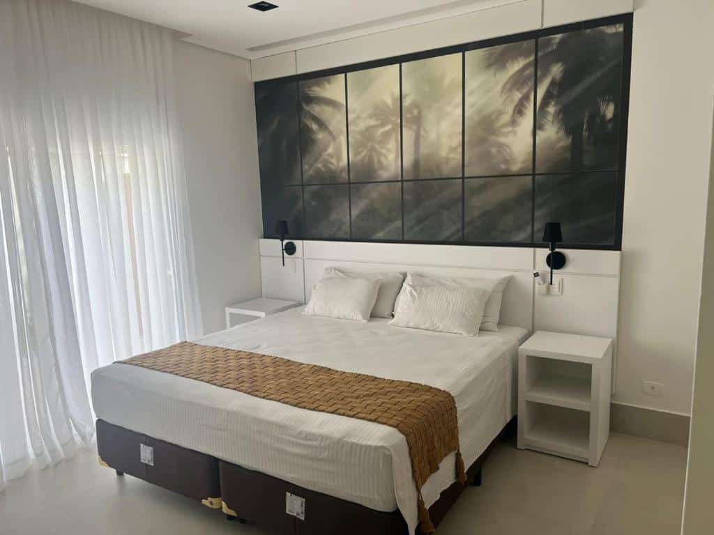 Quarto do Vistabela Resort & Spa com cama de casal no centro do ambiente com uma cômoda em cada lado da cama. Representa hotéis em São Sebastião.