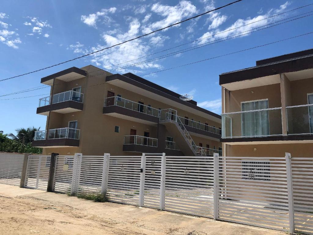 Fachada do Rafael Apartamentos 800m da Praia da Maranduba com dois prédios de três andares na cor marrom com janelas e sacadas de vidro e grade branca como portão. Imagem ilustrando post Airbnb em Maranduba.