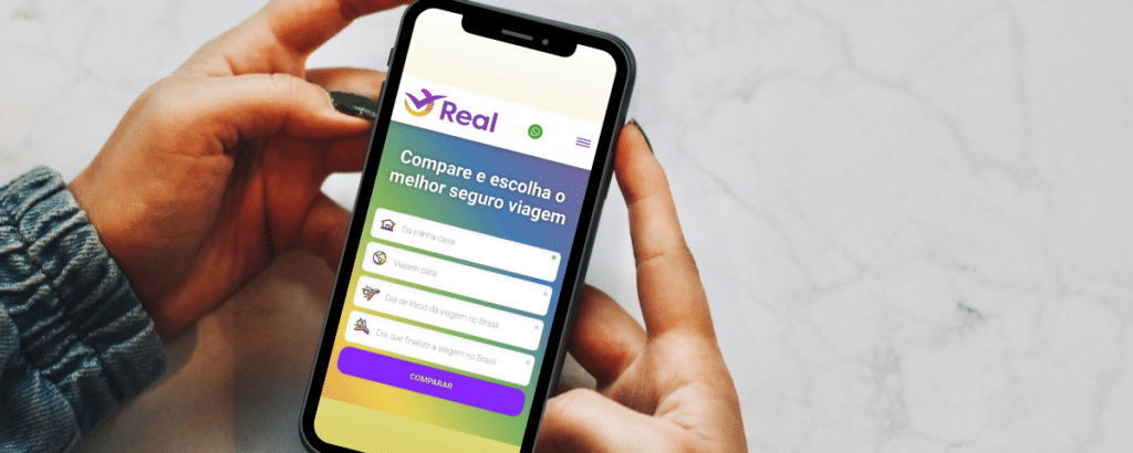 Duas mãos negras apoiadas em uma mesa branca segurando um celular com a tela aberta no site da Real Seguro Viagem