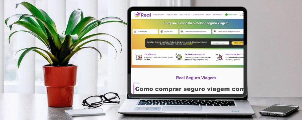 Um notebook aberto em uma mesa com um vaso de planta ao lado com um óculos apoiado na mesa, no eletrônico está aberto o site da Real Seguro Viagem