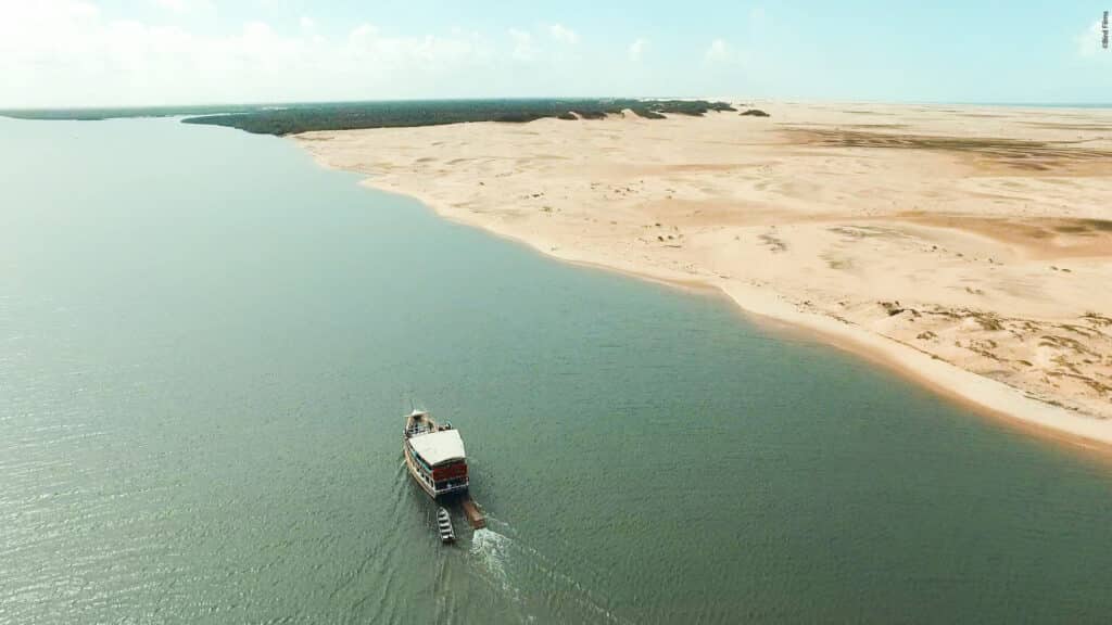 Barco navegando no Rio São Francisco, com as dunas móveis (enormes bancos de areia) à direita